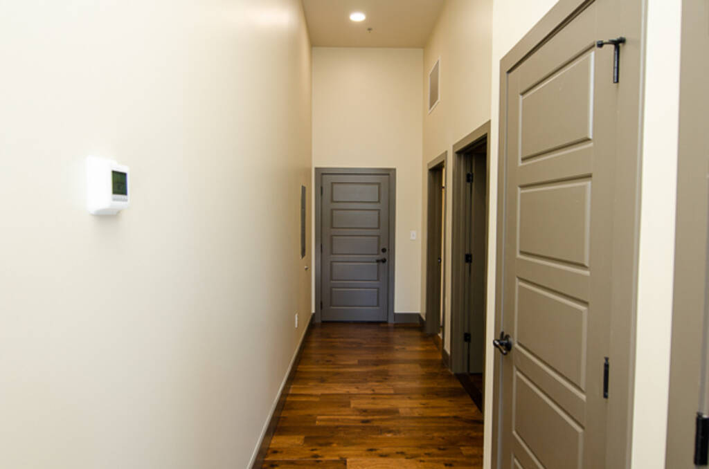 Loft 2D Hallway view of white walls, wood floors, and doors to rooms 