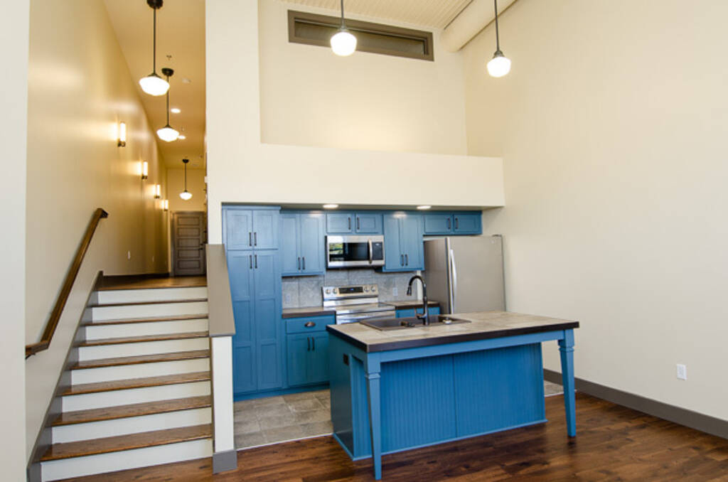 LOFT 2F VIEW OF KITCHEN WITH BLUE CABINETS AND ISLAND FROM LIVING ROOM STAIRS TO LEFT